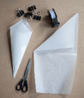 Tutka z papieru do pieczenia, krok 1: odcinamy pasek papieru o szerokości = połowie szerokości całego papieru. Zaginamy papier oznaczając środek i przekątną jednej połowy.